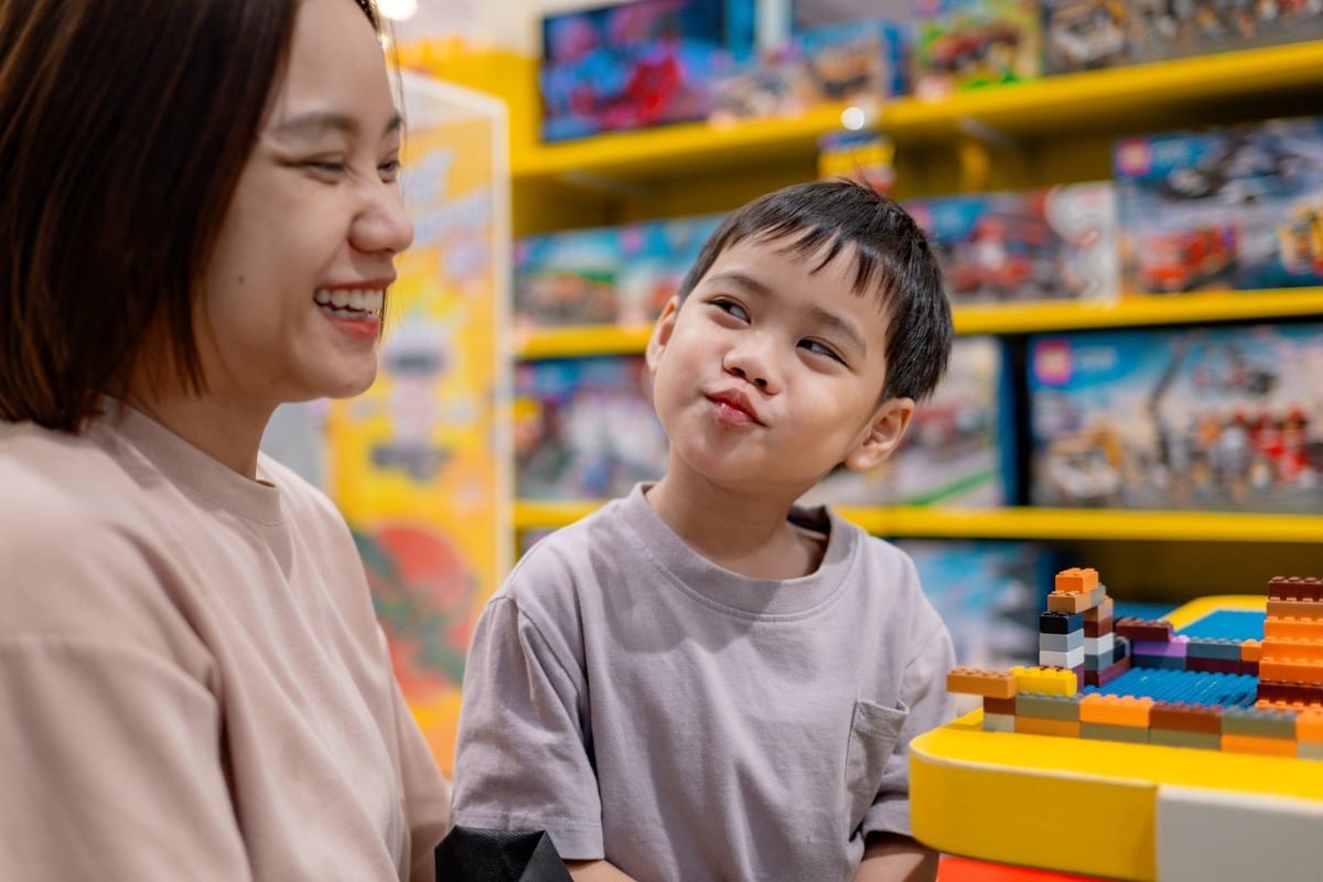 Cheerful mom and child constructing colorful building blocks, sharing playful bonding moment inside children's toy shop