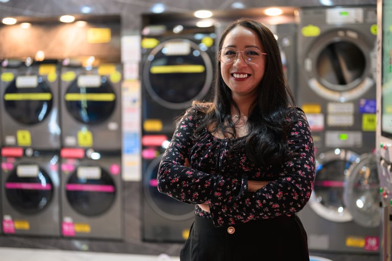 Asian woman standing confidently in self-service laundromat with washing machines in background