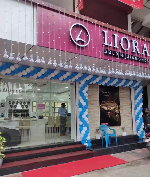 LIORA Gold and Diamonds jewelry store storefront with pink and white signage, blue and white balloon decorations, and glass entrance with red carpet