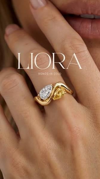Close-up of hand wearing LIORA gold ring with white and yellow diamond stones set in curved gold band
